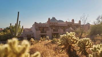 Edificio de estilo desértico con varios balcones y montañas al fondo.