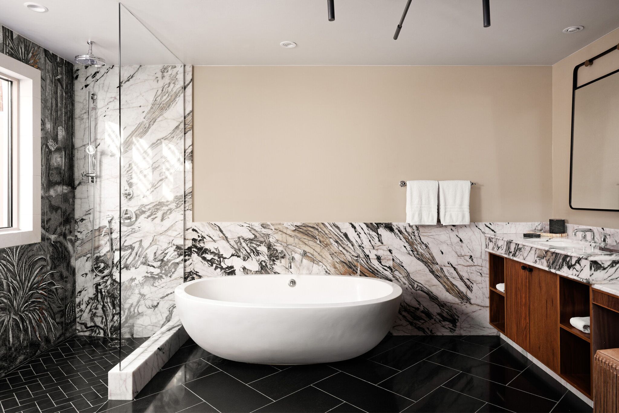A modern bathroom with a freestanding bathtub, marble walls, and a wooden vanity.