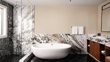A modern bathroom with a freestanding bathtub, marble walls, and a wooden vanity.