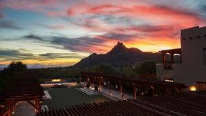 Terraza en la azotea con vista a una montaña al atardecer, mobiliario exterior y una estructura de pérgola.