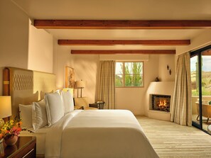 A hotel room with a large bed, a fireplace, a window with curtains, and a view of the outdoors.