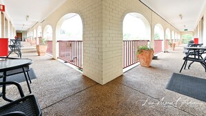 A covered outdoor area with brick columns, tables, and chairs.