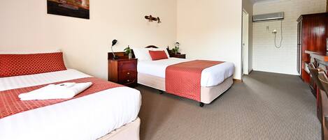 A hotel room with two beds, a wardrobe, a shower, and a painting on the wall.