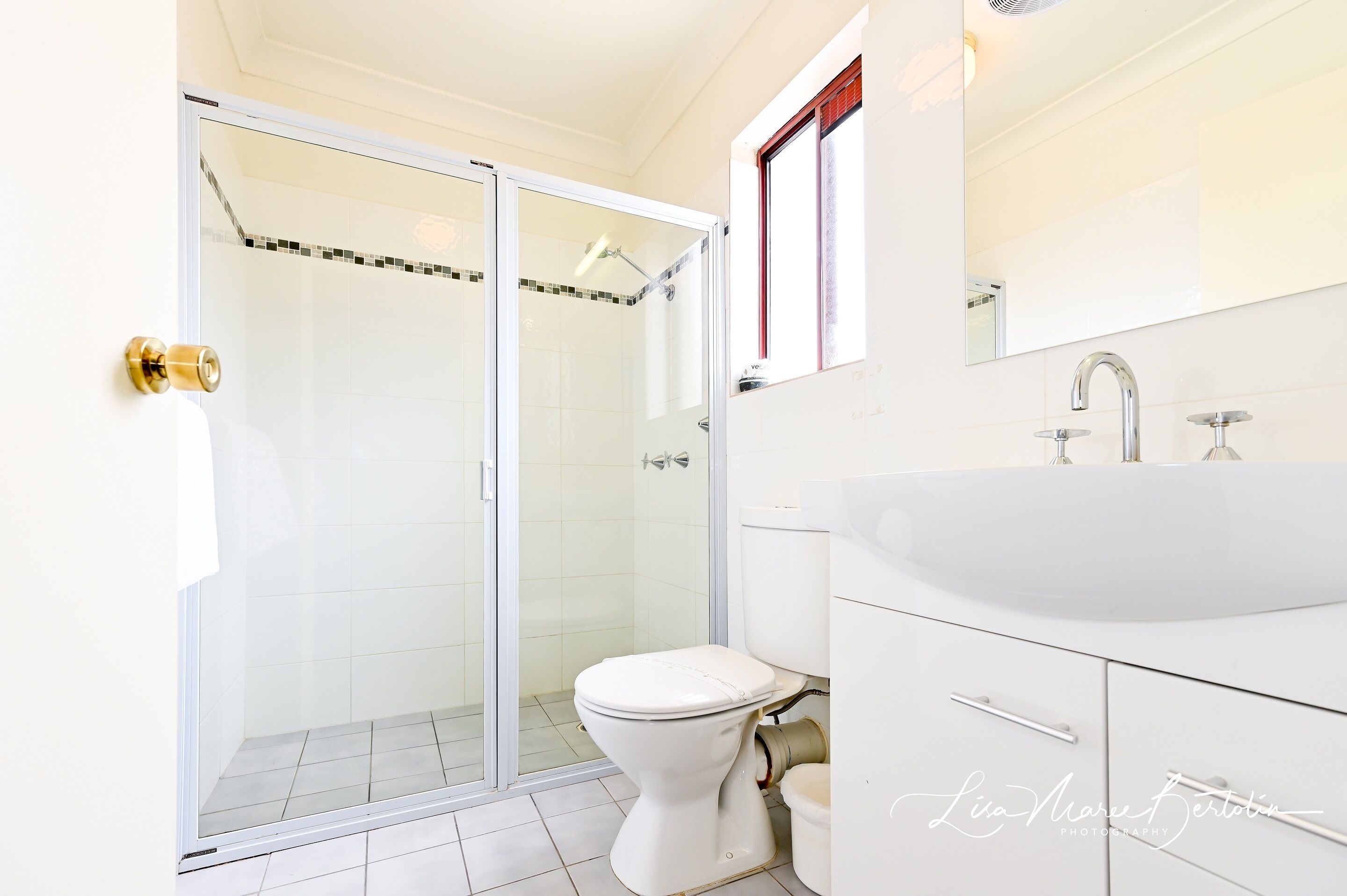 A modern bathroom with a glass-enclosed shower, a white toilet, and a vanity with a sink and mirror.