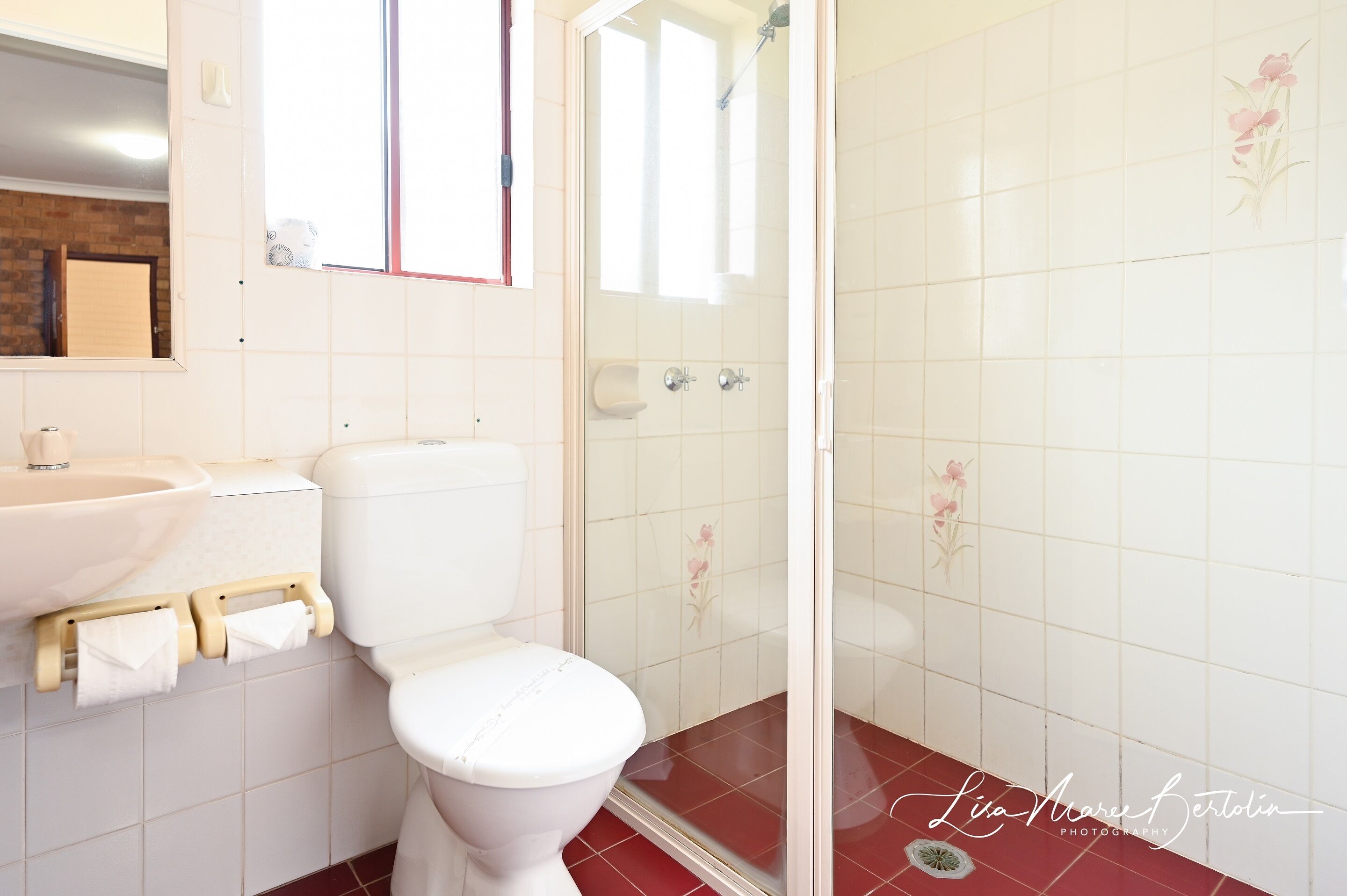 Baño con inodoro, lavamanos y zona de ducha.