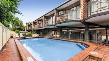 Una piscina al aire libre, sombrillas, sillones reclinables de piscina