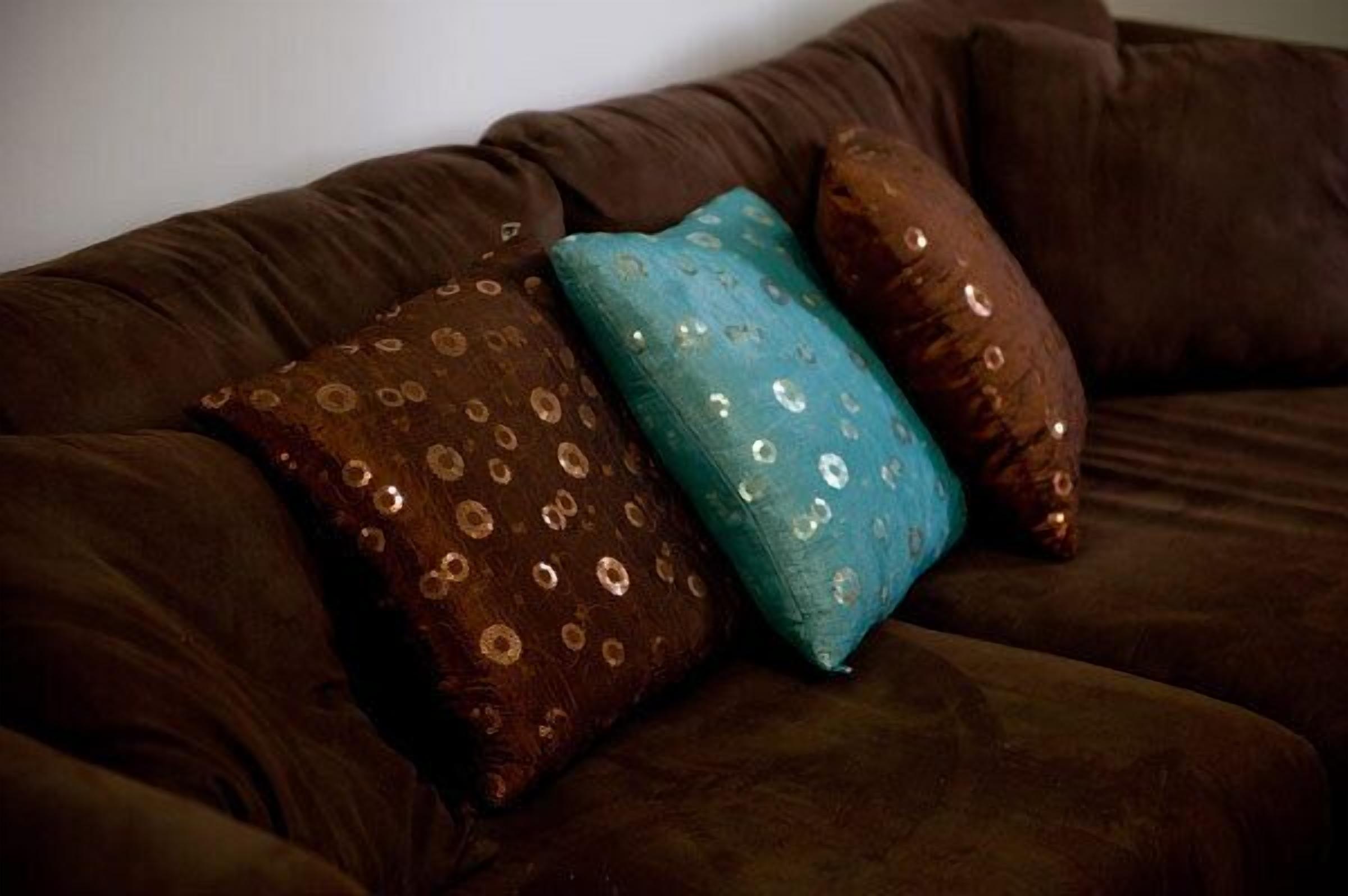 Un canapé marron agrémenté de trois coussins décoratifs.