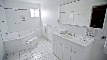 Ein modernes Badezimmer mit einer großzügigen Badewanne, einem Doppelwaschbecken und einem großen Spiegel.