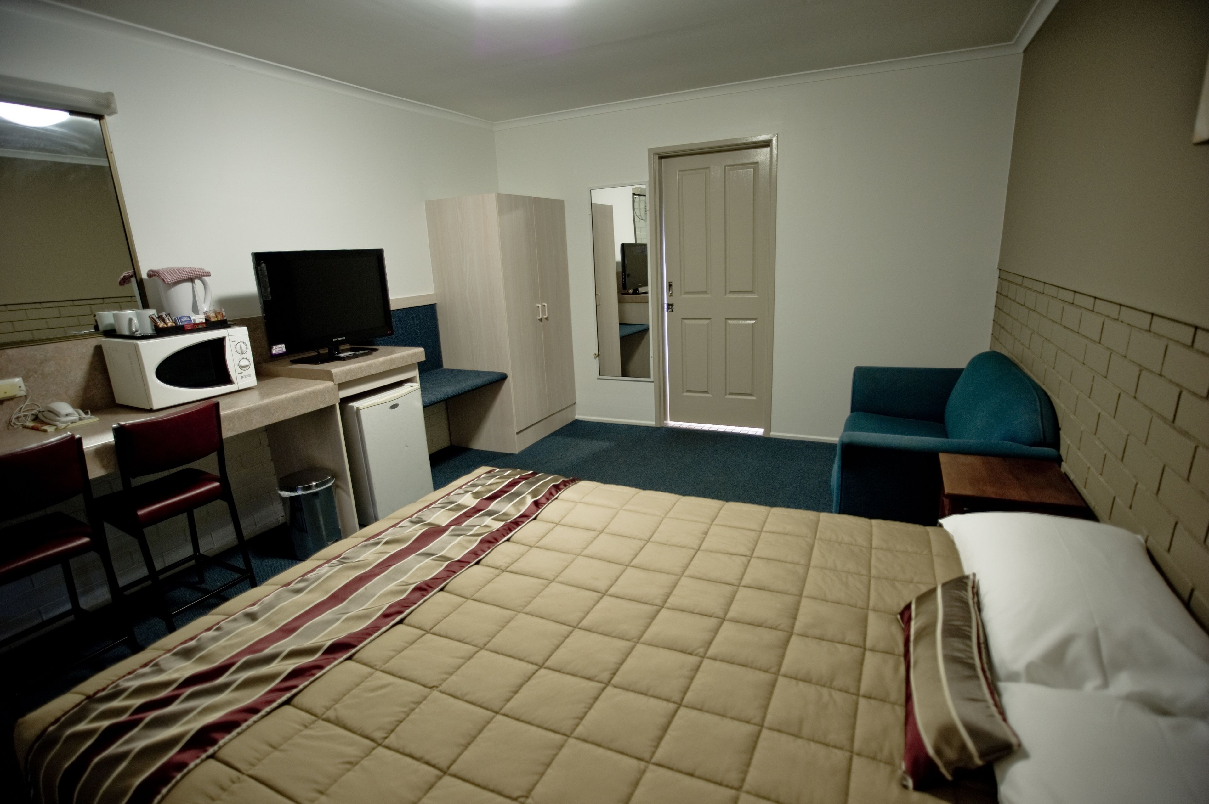 Una habitación de hotel con cama, escritorio con computadora, microondas y televisión.