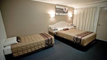 A hotel room with two beds, a headboard, a wall-mounted artwork, and a door with curtains.