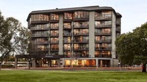 A multi-story hotel with balconies, large windows, and a well-maintained lawn. - Rydges South Park Adelaide (Adelaide)