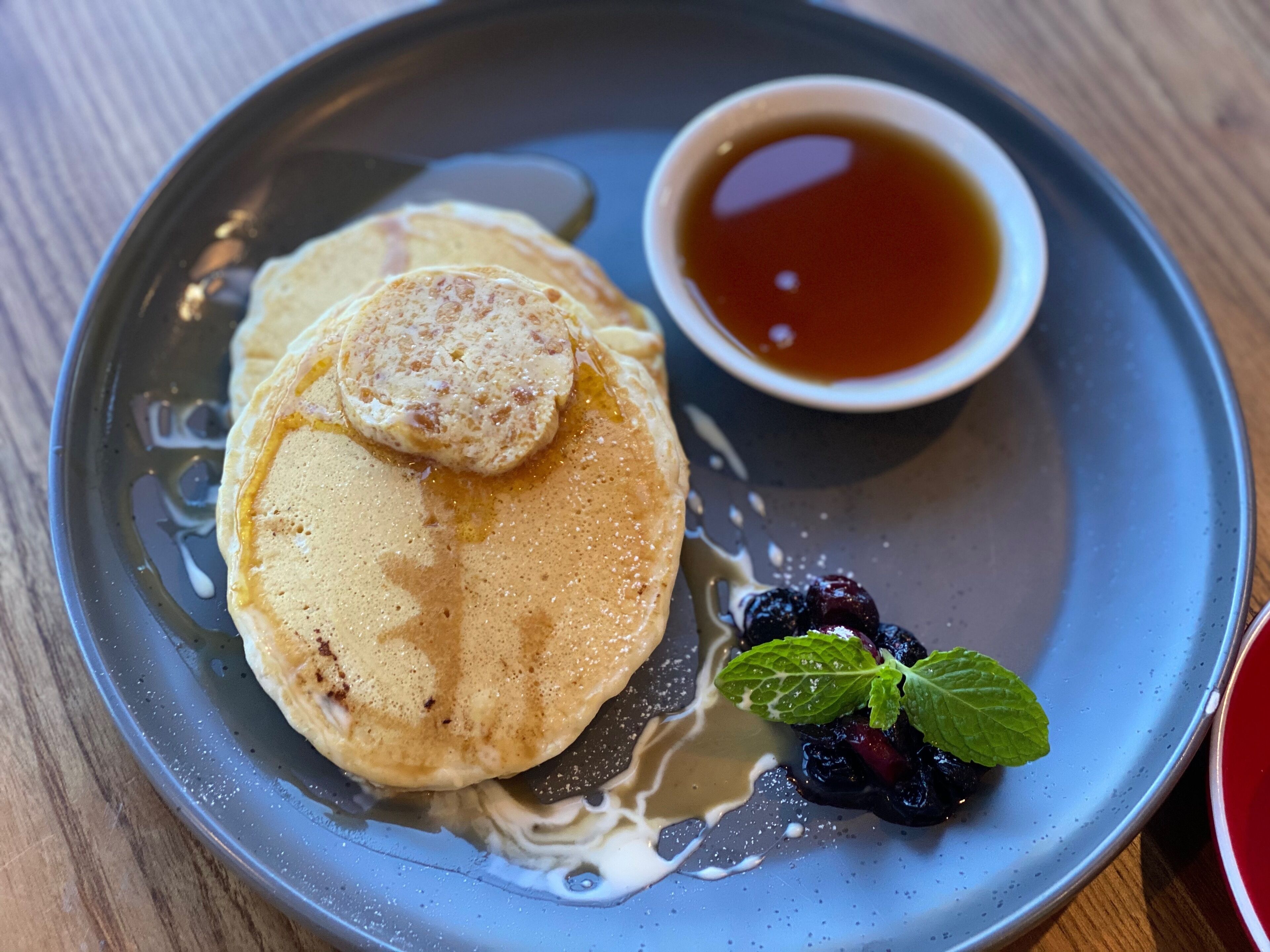 A plate with pancakes, syrup, and a small bowl of syrup.