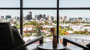 A view from a window with a cityscape, a vase with flowers, and a table with chairs. - Rydges South Park Adelaide (Adelaide)