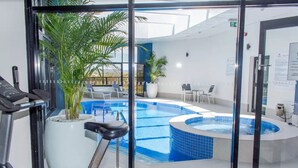 An indoor swimming pool with a hot tub, exercise equipment, and seating areas. - Rydges South Park Adelaide (Adelaide)