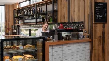 A coffee shop with a menu board, a display of pastries, and a bar area with various bottles.