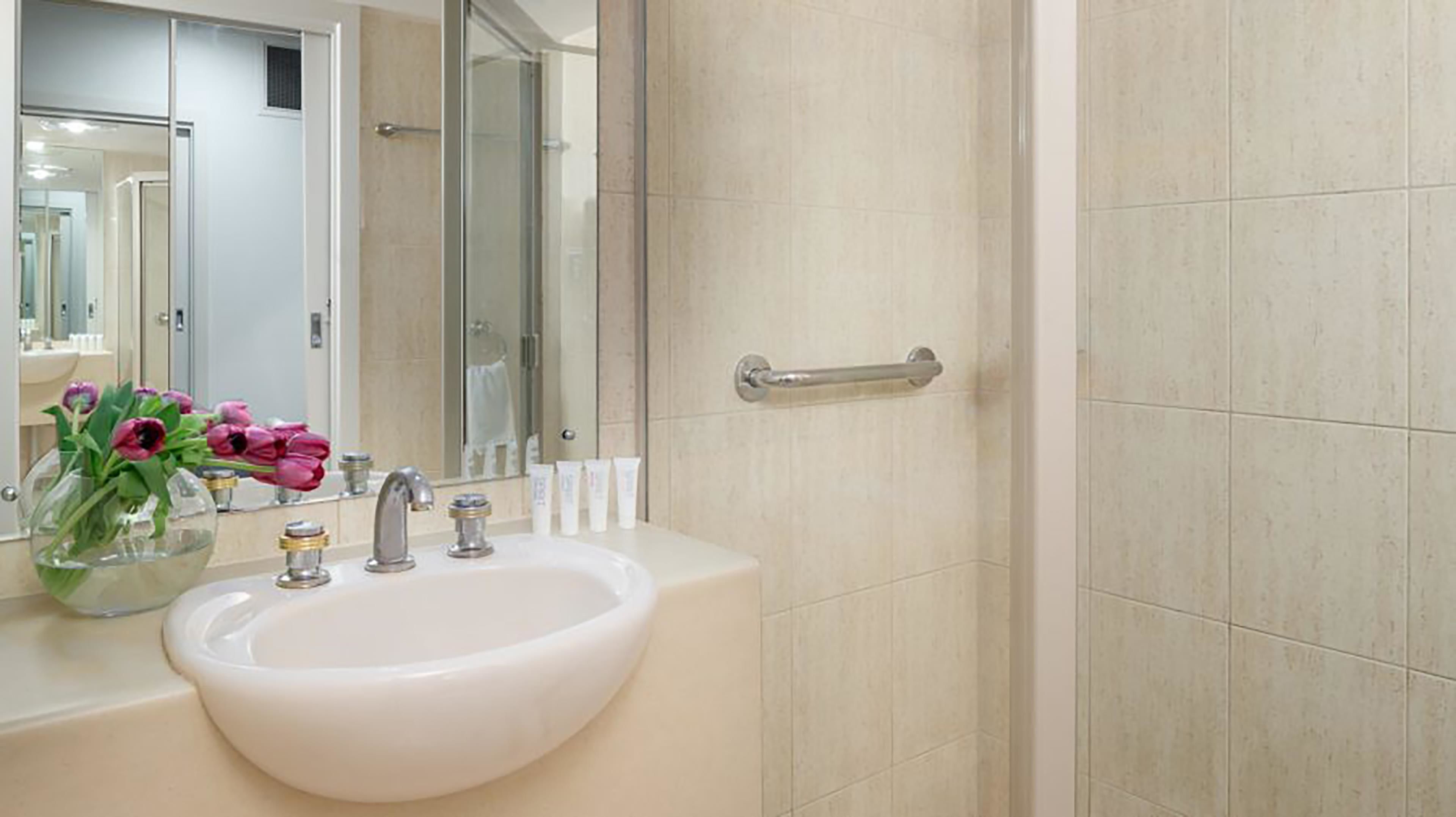 A bathroom with a white sink, a mirror, and a glass shower enclosure.