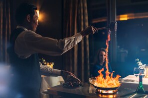 A person cooking with flames on a stove in a dimly lit room. - Wrest Point (Sandy Bay)