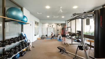 A gym with exercise equipment, a bench, and a punching bag.