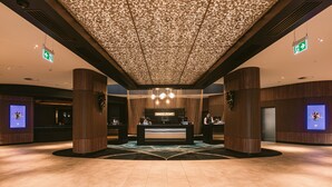 Un hall d’entrée moderne avec un comptoir d’accueil, des panneaux de bois et un plafond orné de motifs.