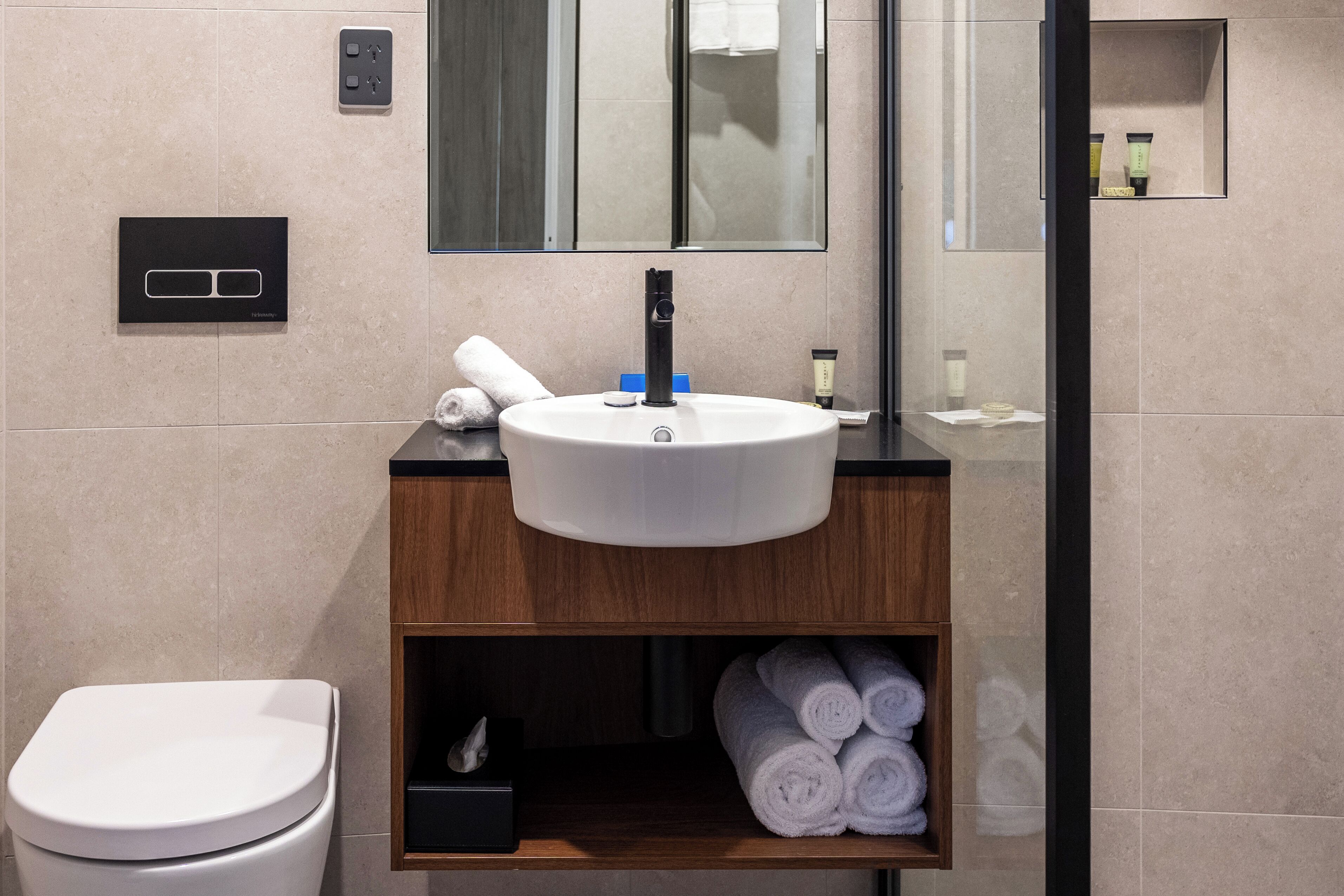 A modern bathroom with a white sink, wooden vanity, and a toilet.