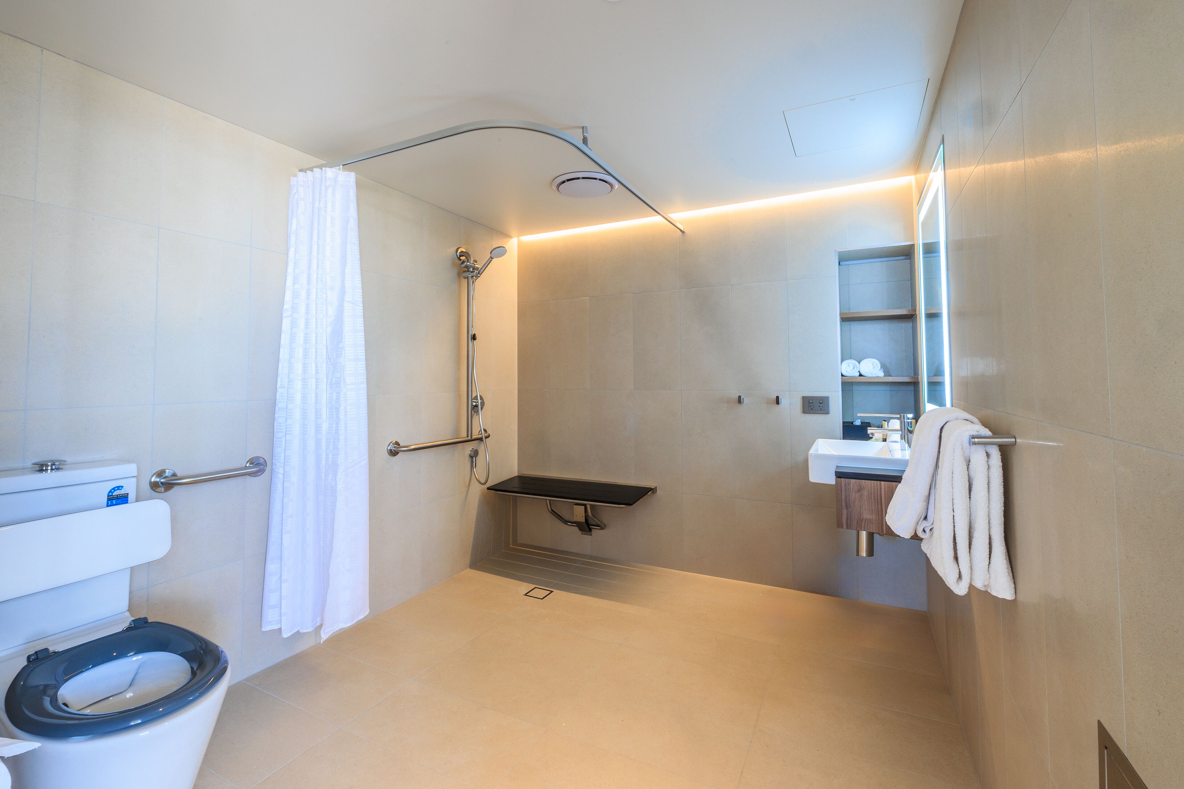 A modern bathroom with a toilet, shower, and sink.