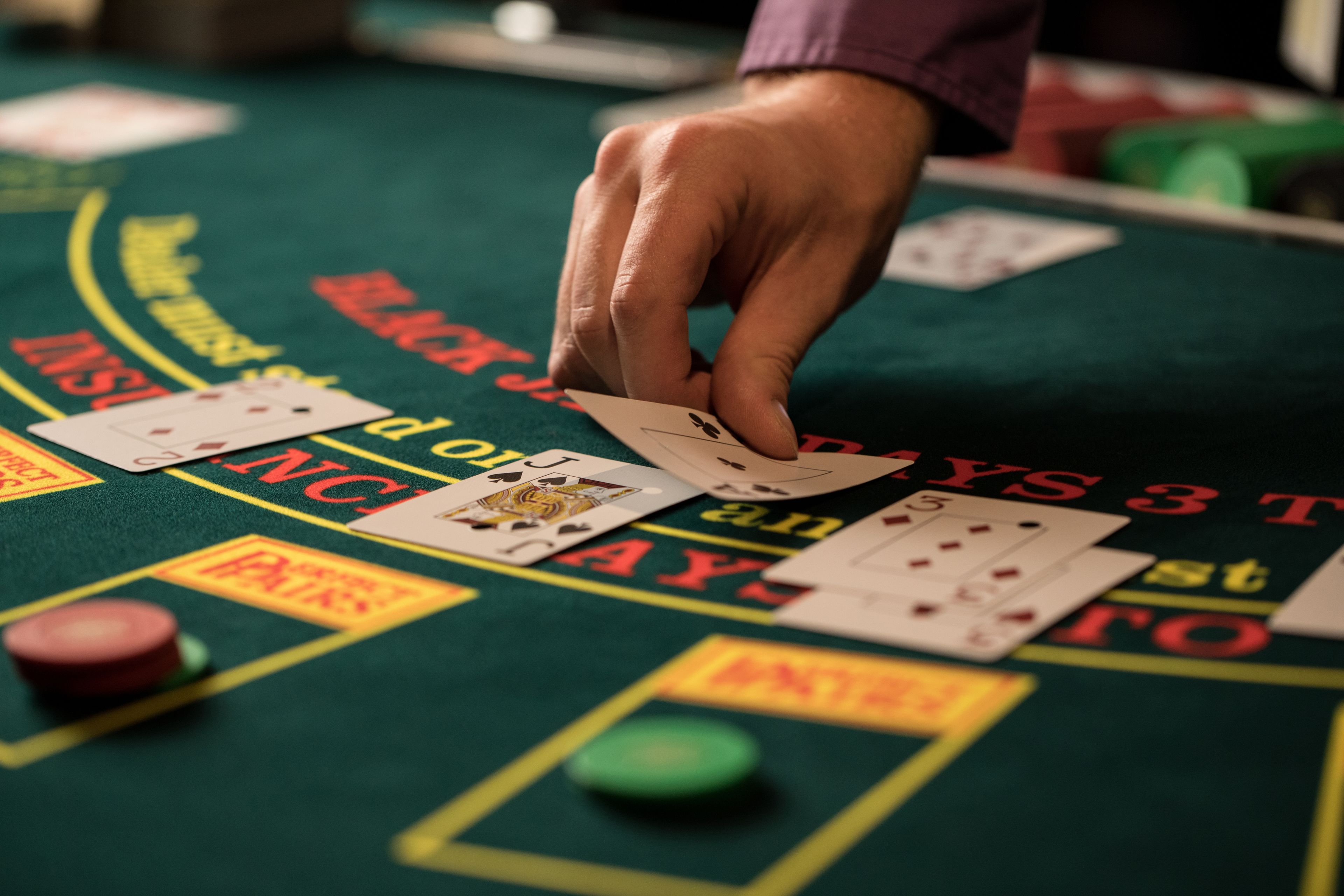 A hand dealing cards on a casino table with betting areas marked.