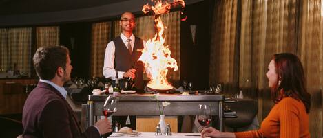 Un restaurante con un camarero haciendo un truco de fuego en la mesa.