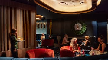 A modern lounge area with wooden paneling, red seating, and a decorative wall with a circular pattern.