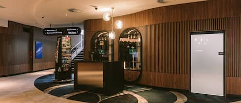 A hotel lobby with a reception desk, a staircase, and directional signs.