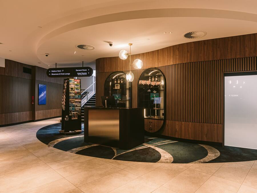 A hotel lobby with a reception desk, a staircase, and directional signs.