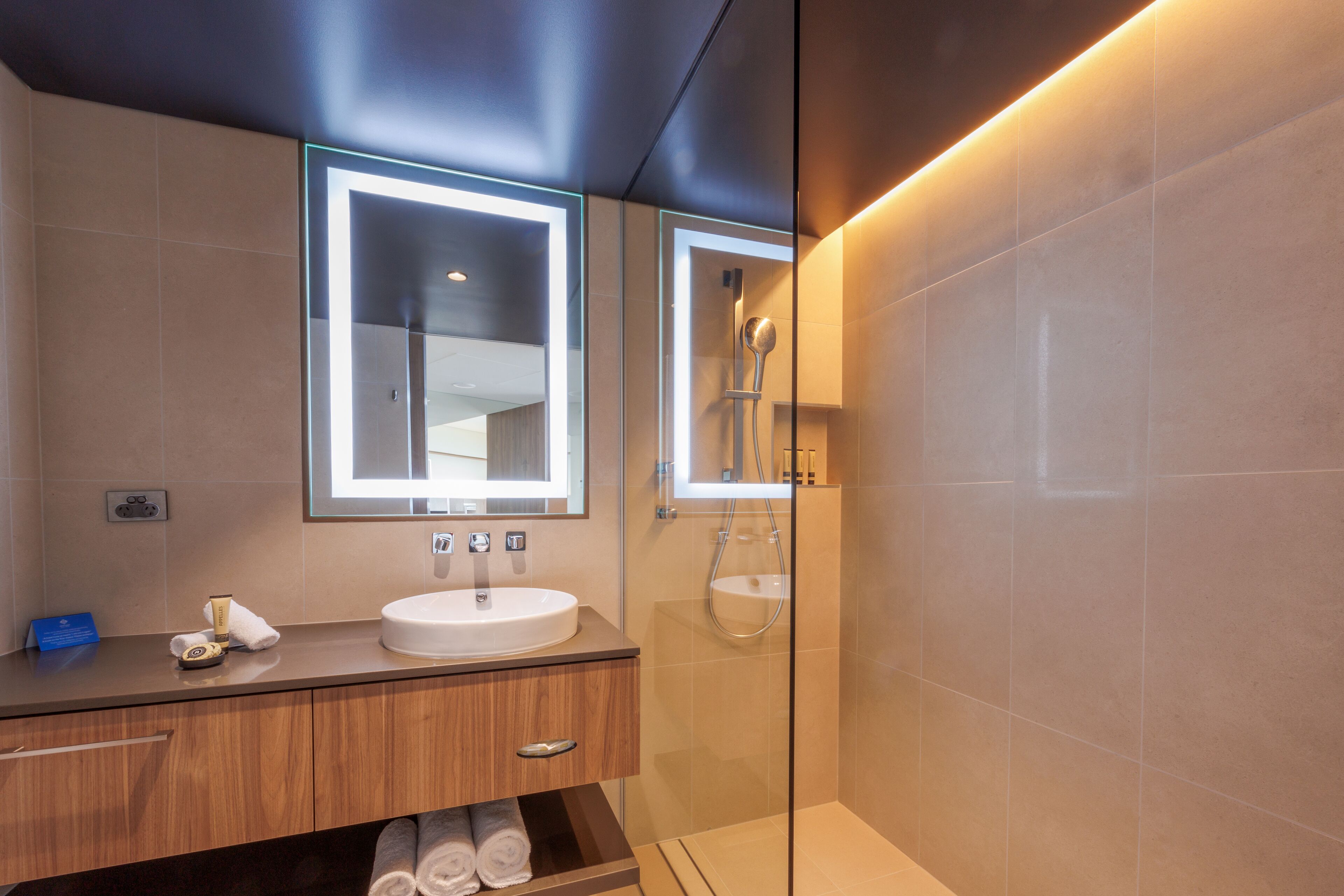 A modern bathroom with a vanity, a mirror, a shower, and a glass-enclosed shower area.