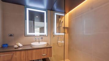 A modern bathroom with a vanity, a mirror, a shower, and a glass-enclosed shower area.