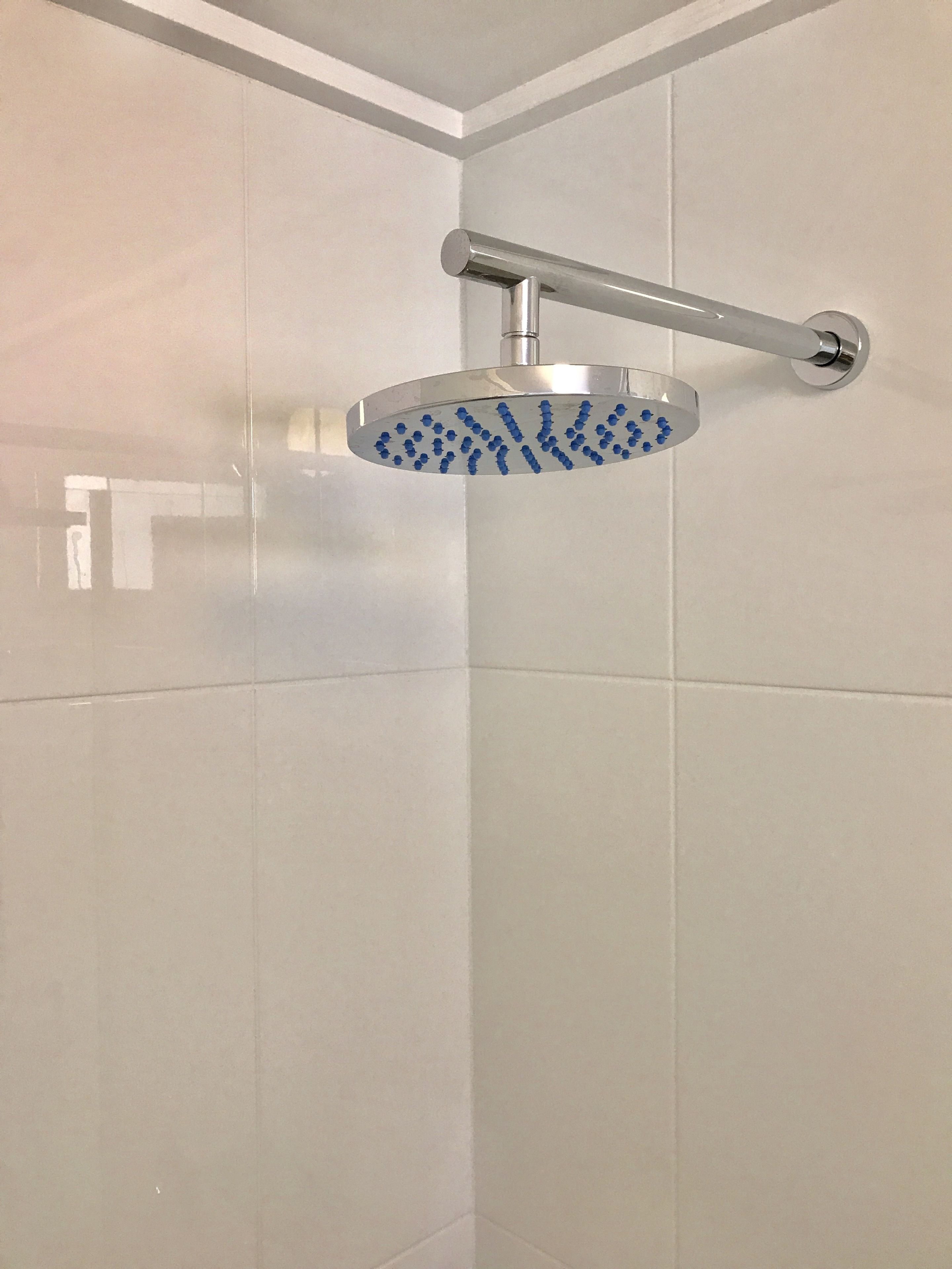 A shower with a handheld spray head mounted on a wall.
