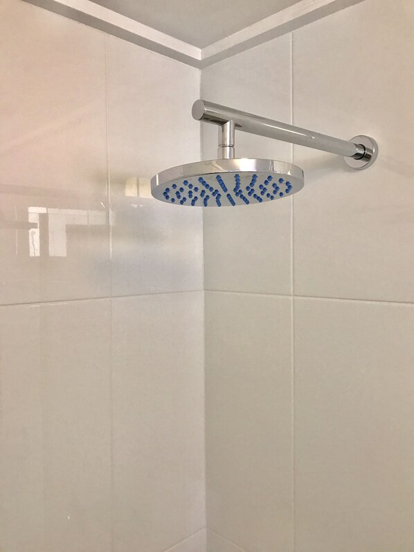 Una ducha con cabezal de ducha manual fijado a la pared.