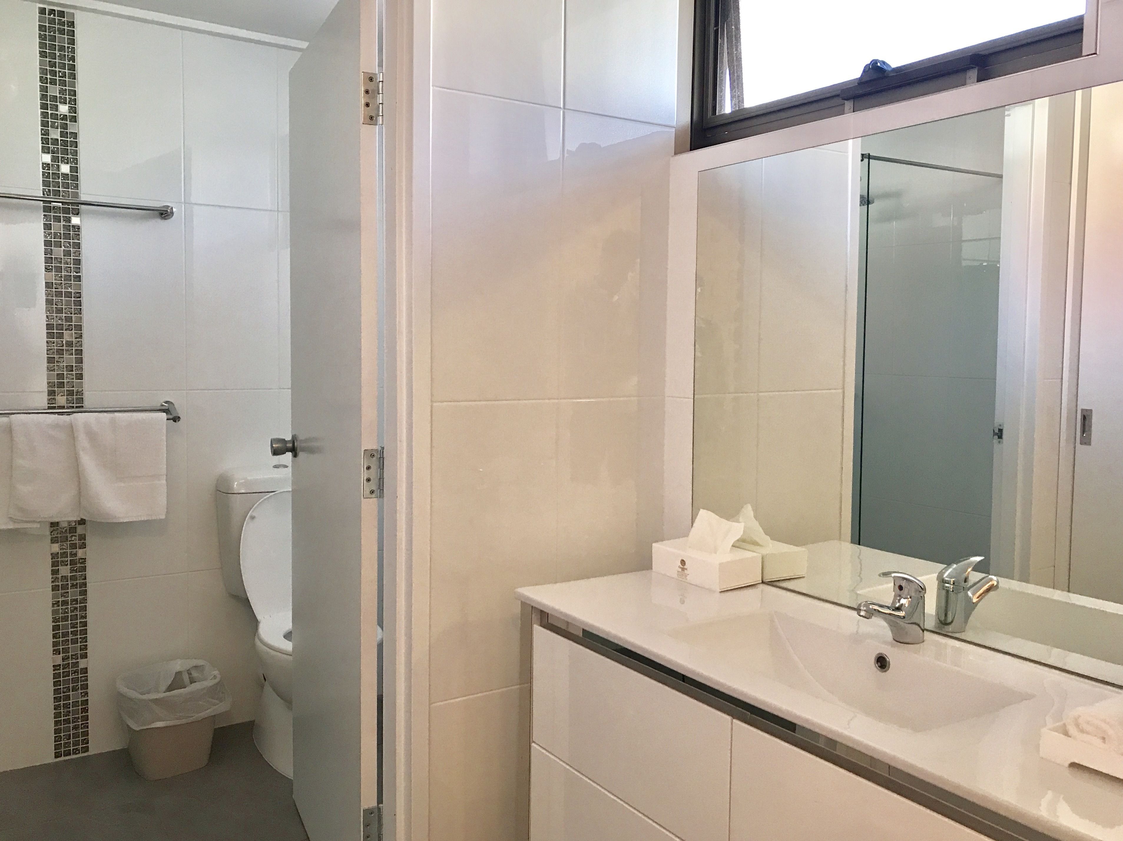Une salle de bain moderne avec des toilettes, un lavabo et un grand miroir.