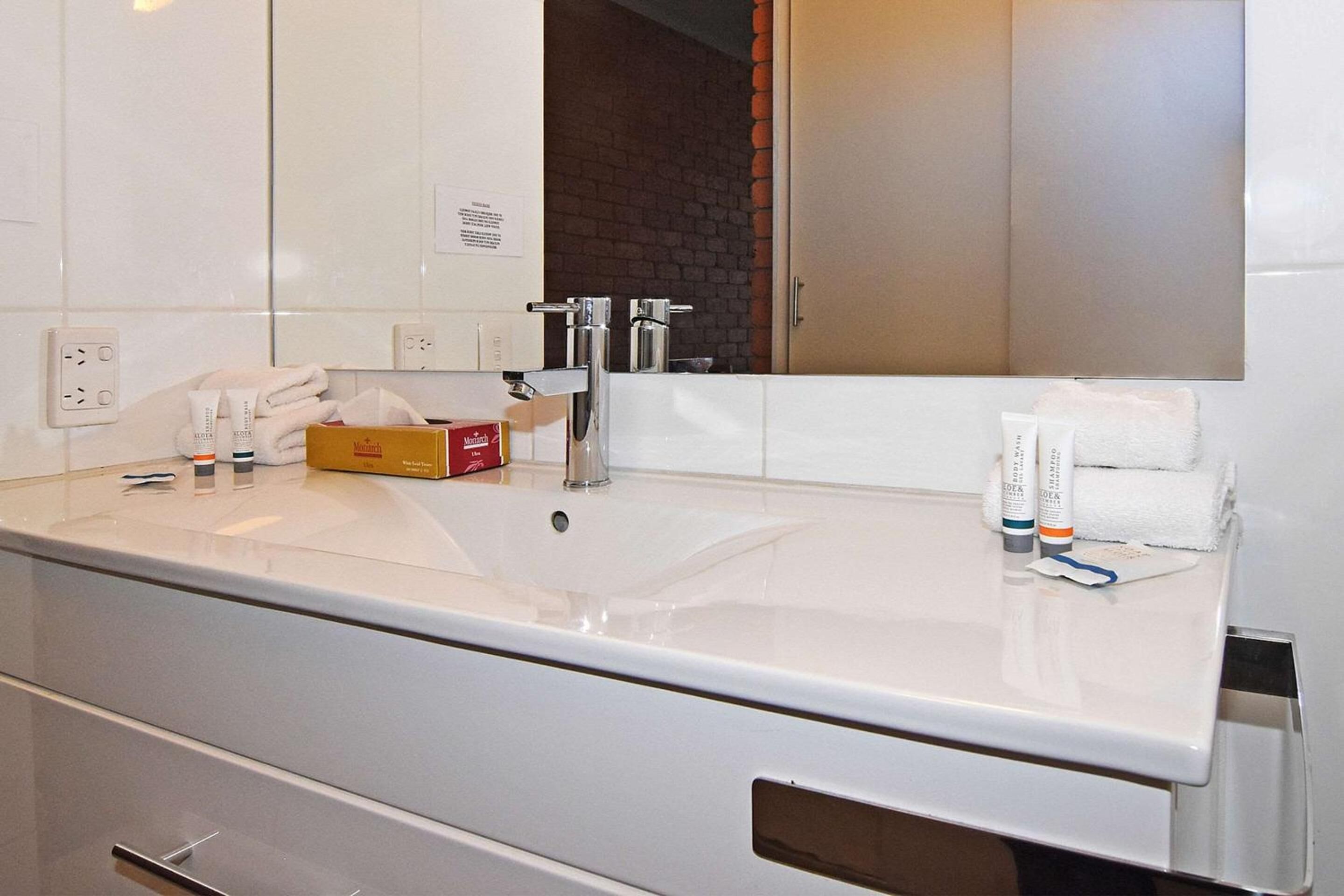 Ein modernes Badezimmer mit einem großen weißen Waschbecken, einem Spiegel und Toilettenartikeln.