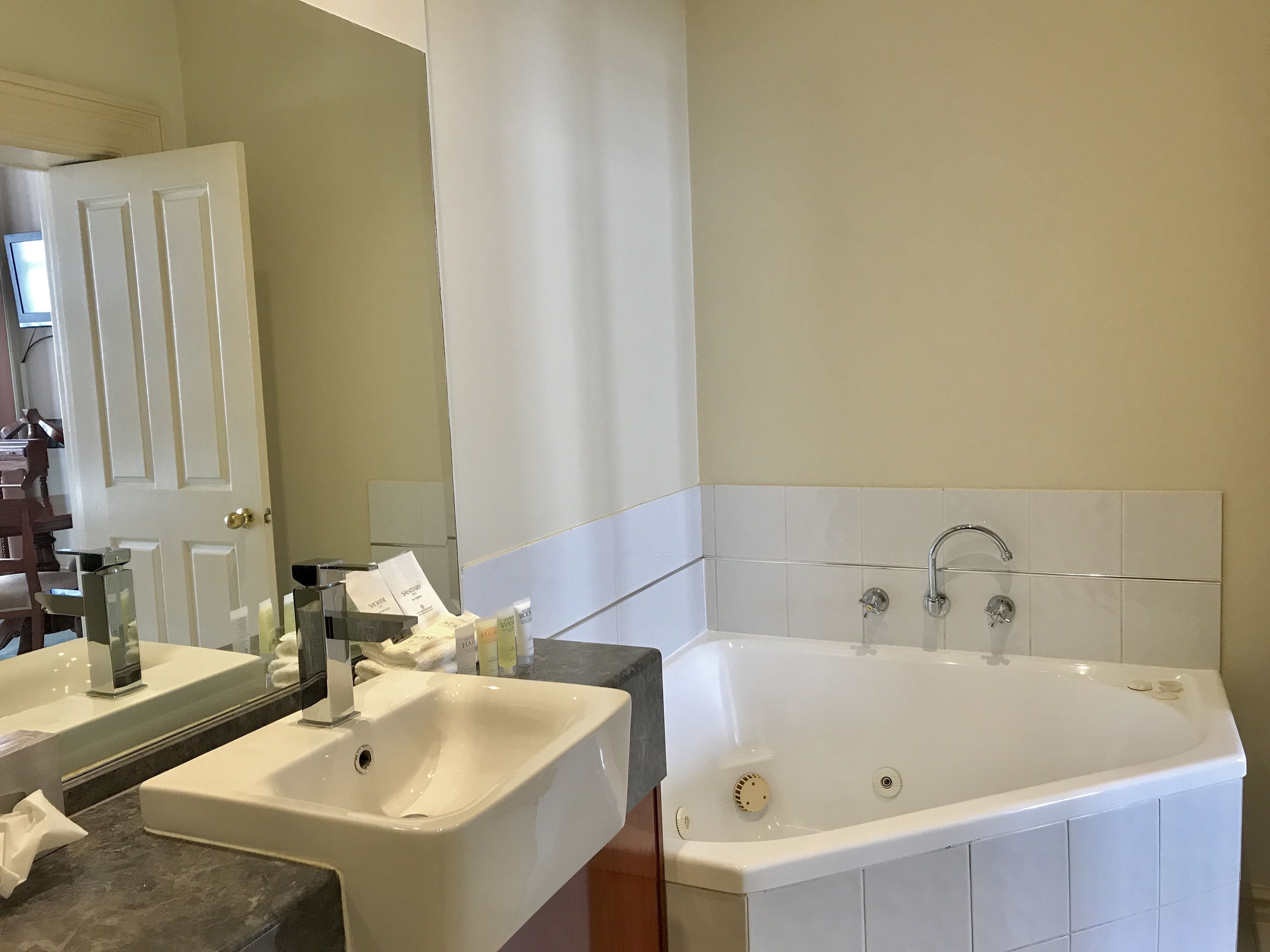 A bathroom with a large bathtub, a sink, and a mirror.
