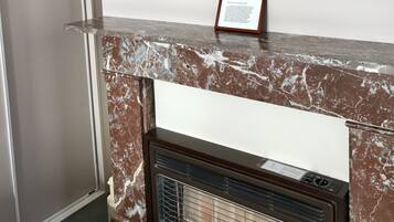 A marble fireplace with a framed painting of flowers above it.