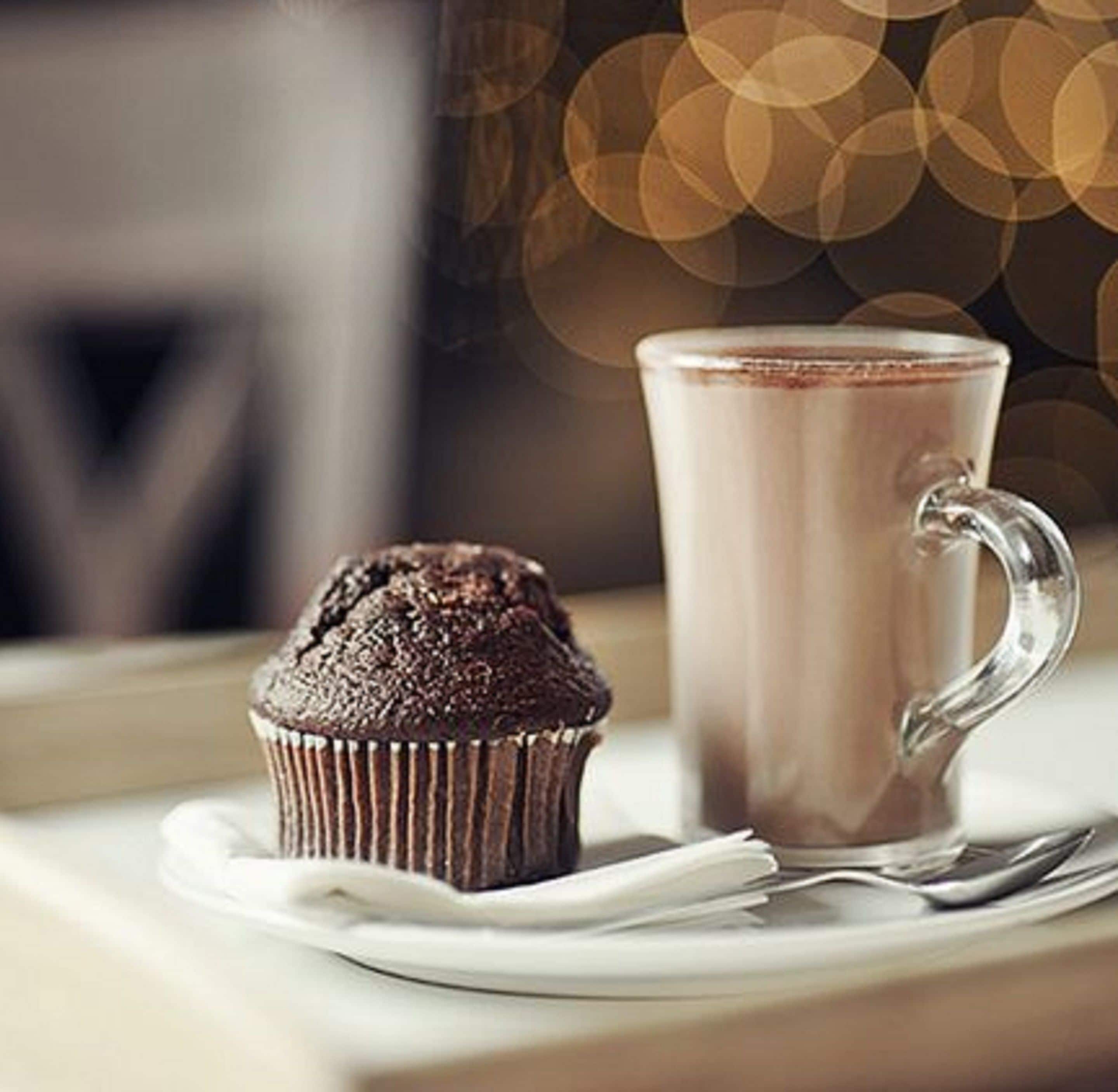 Un muffin i un got sobre una taula.