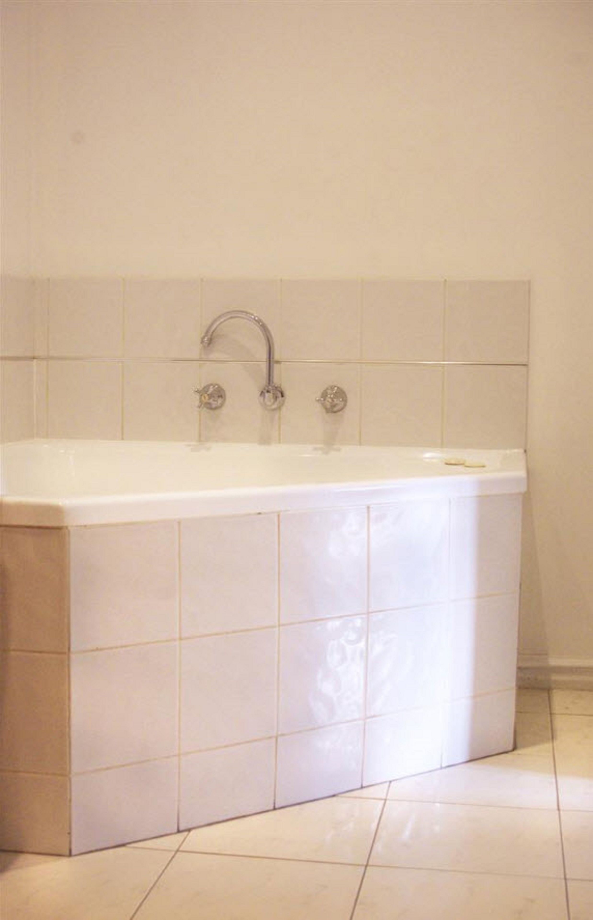 Une baignoire ordinaire, dotée d’un robinet et d’un porte-savon, placée devant un mur carrelé dans une salle de bain.