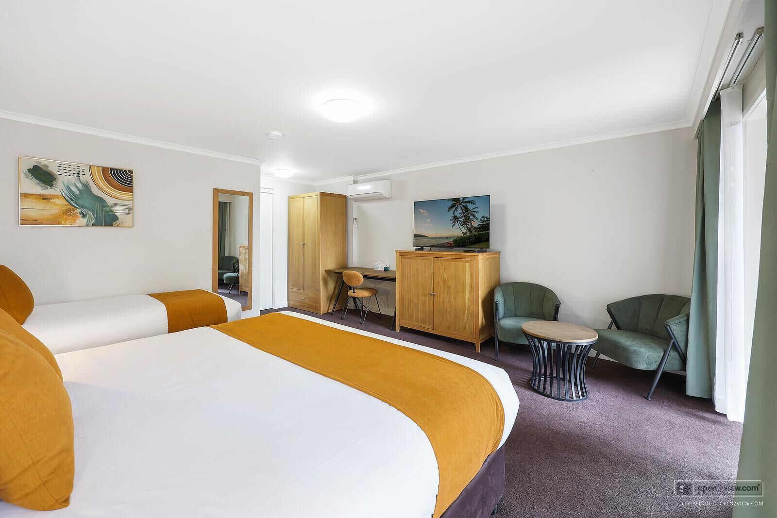 A hotel room with a large bed, a desk, a chair, and a TV.