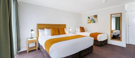 Habitació d'hotel amb un llit gran, una tauleta de nit, un mirall i un quadre a la paret.