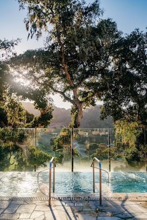 An outdoor swimming pool with a view of trees and distant hills.