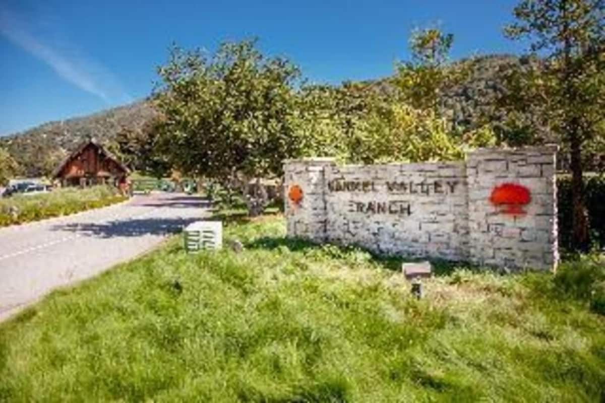 A stone sign with 'KARL WALLEY FRANCH' written on it, a road, and a building in the background.