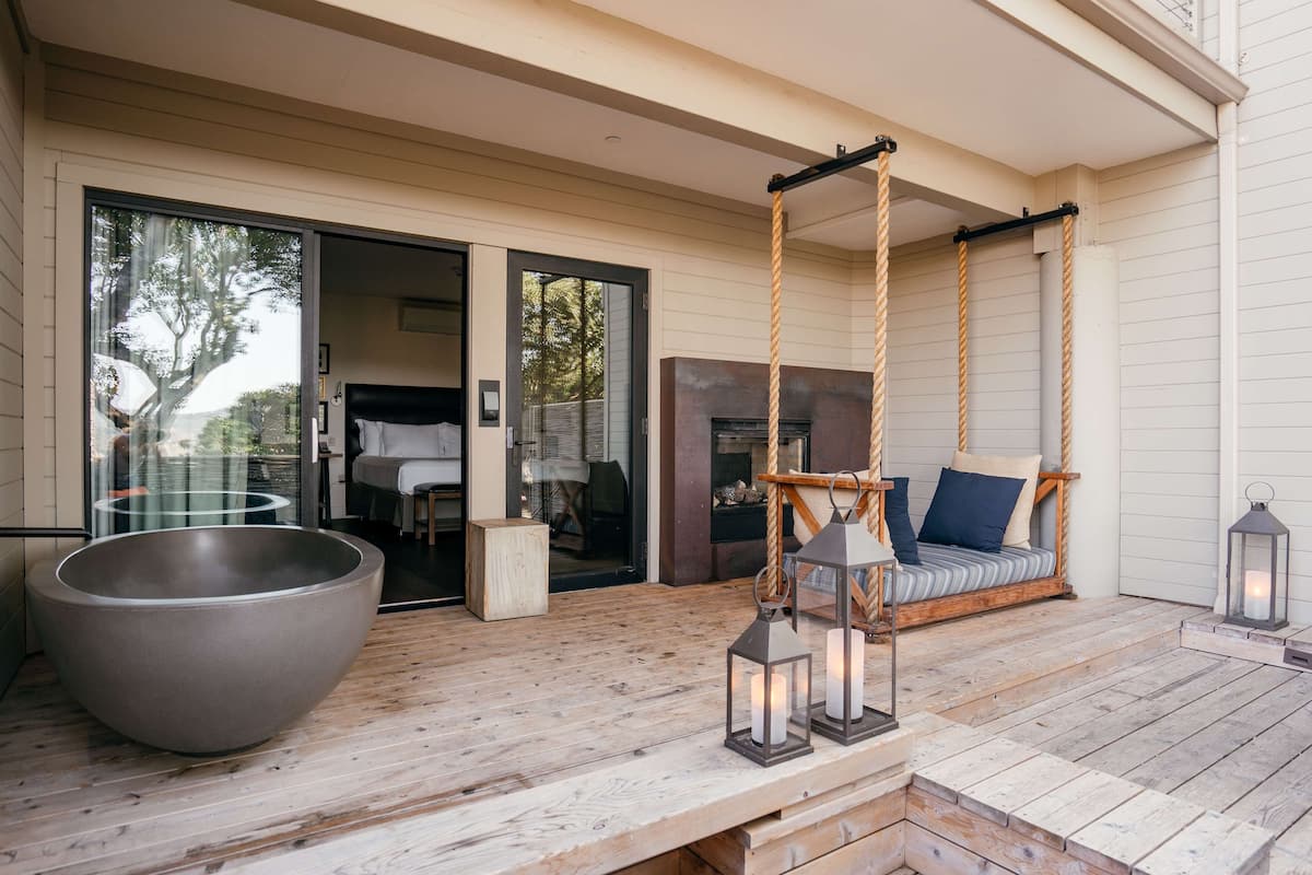 A wooden deck with a large bowl, a swing, and two lanterns.