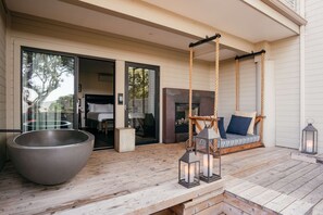 A wooden deck with a large bowl, a swing, and two lanterns.