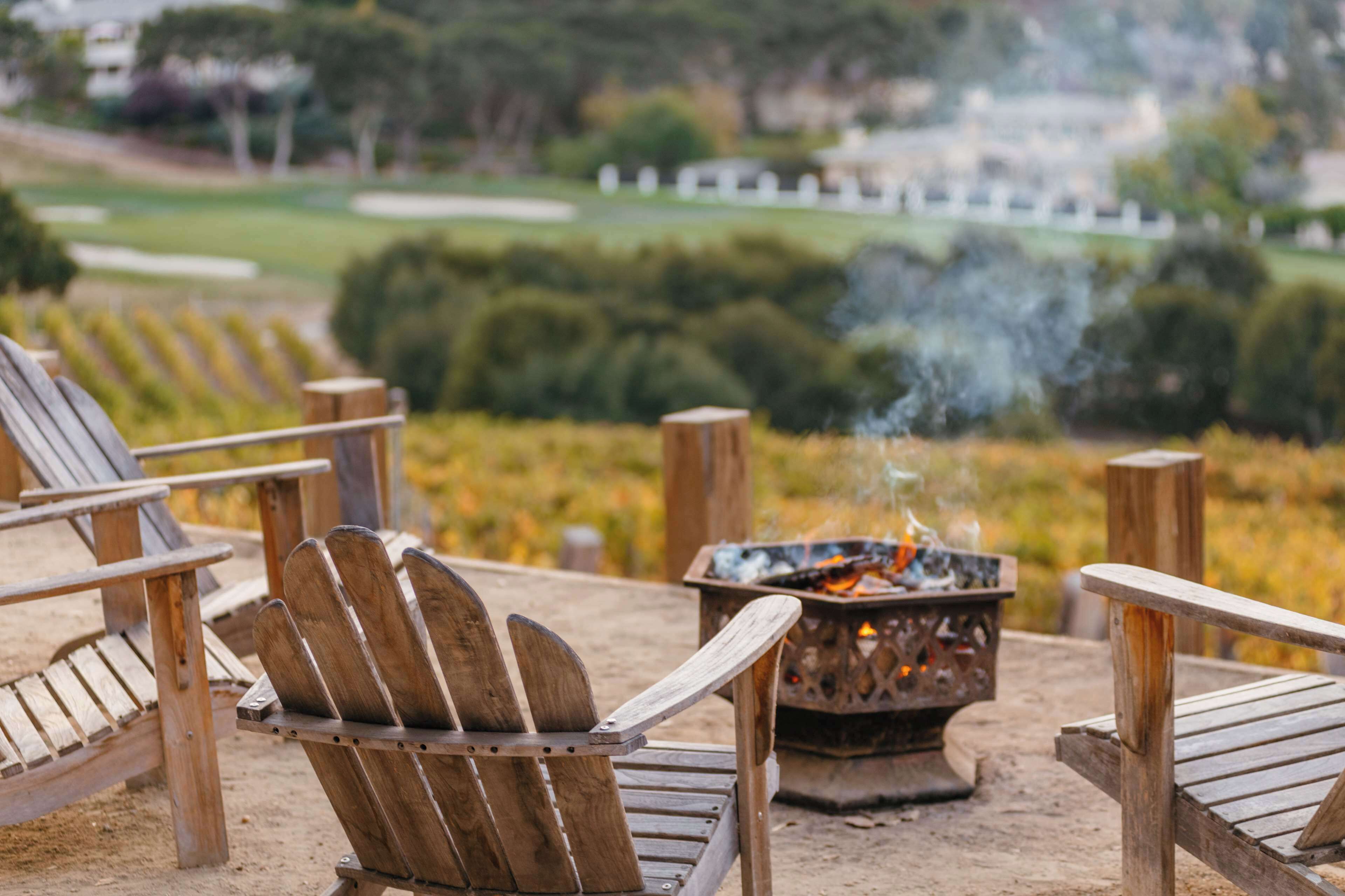 Una terraza de madera con sillas Adirondack y un hogar para fuego.