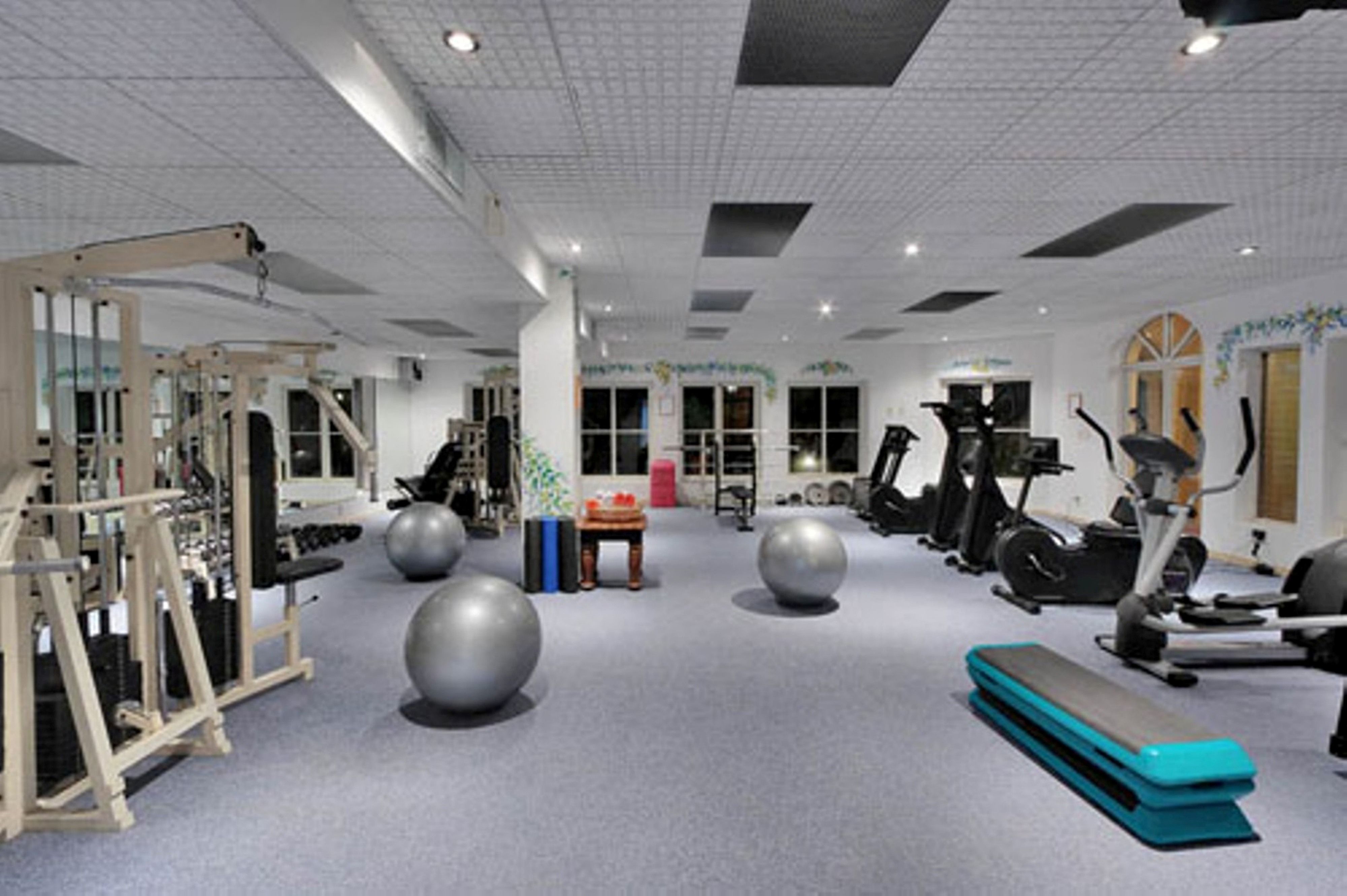A gym with exercise equipment, large exercise balls, and a bench.