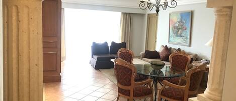 A dining area with a glass table and chairs, a chandelier, and a ceiling fan.