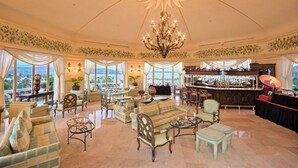 Un'ampia area lounge con varie opzioni di seduta, un bar e ampie finestre che offrono una vista.
